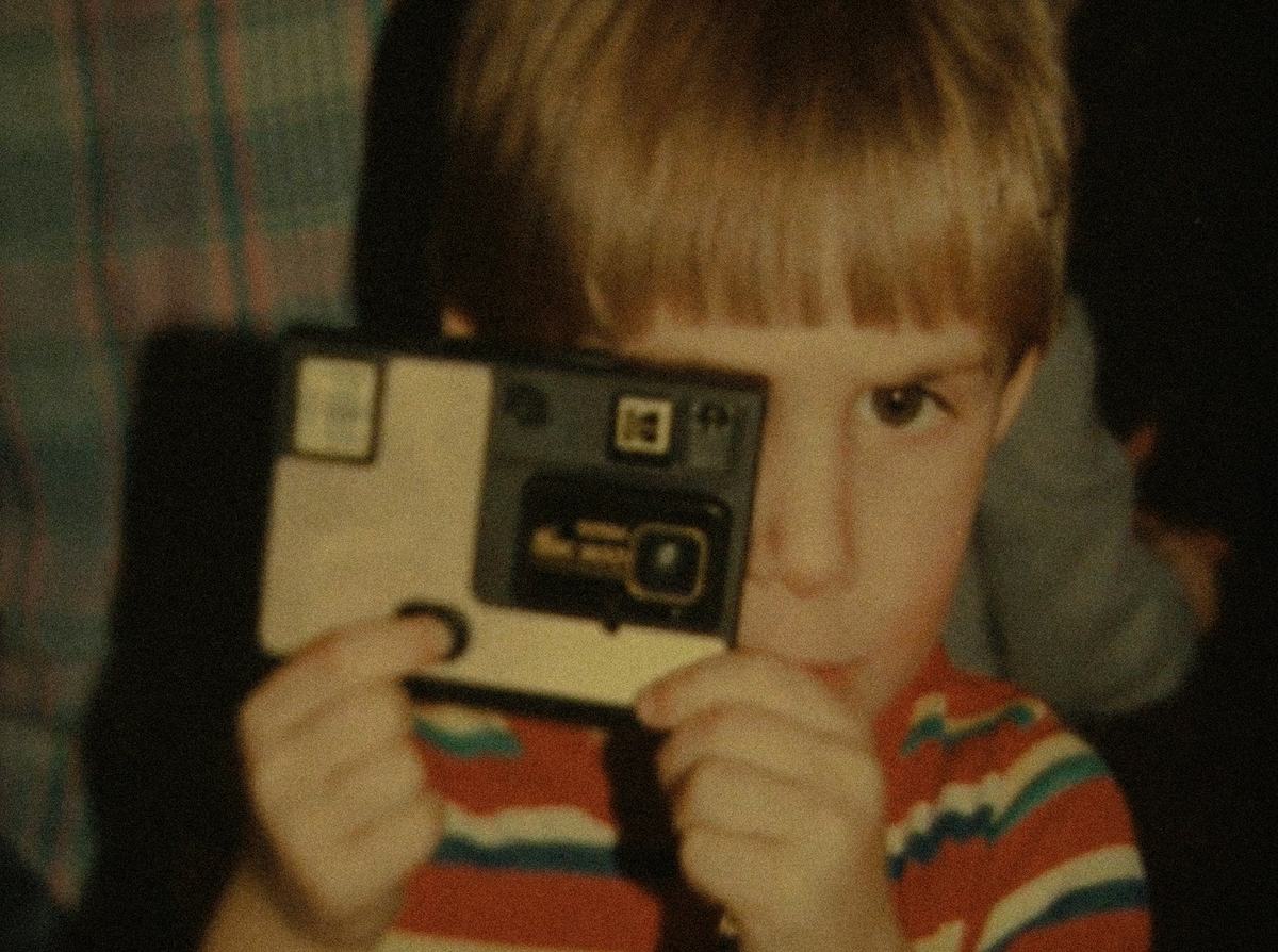 Caleb Heller as a kid, holding a camera up to his eye